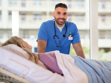 Verpleegkundige staat aan bed bij patiënt 