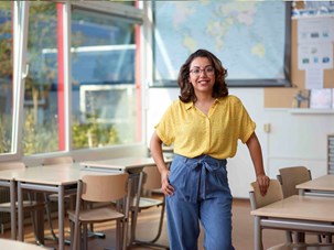 Vrouwelijke onderwijsassistent staat lacht in het leslokaal