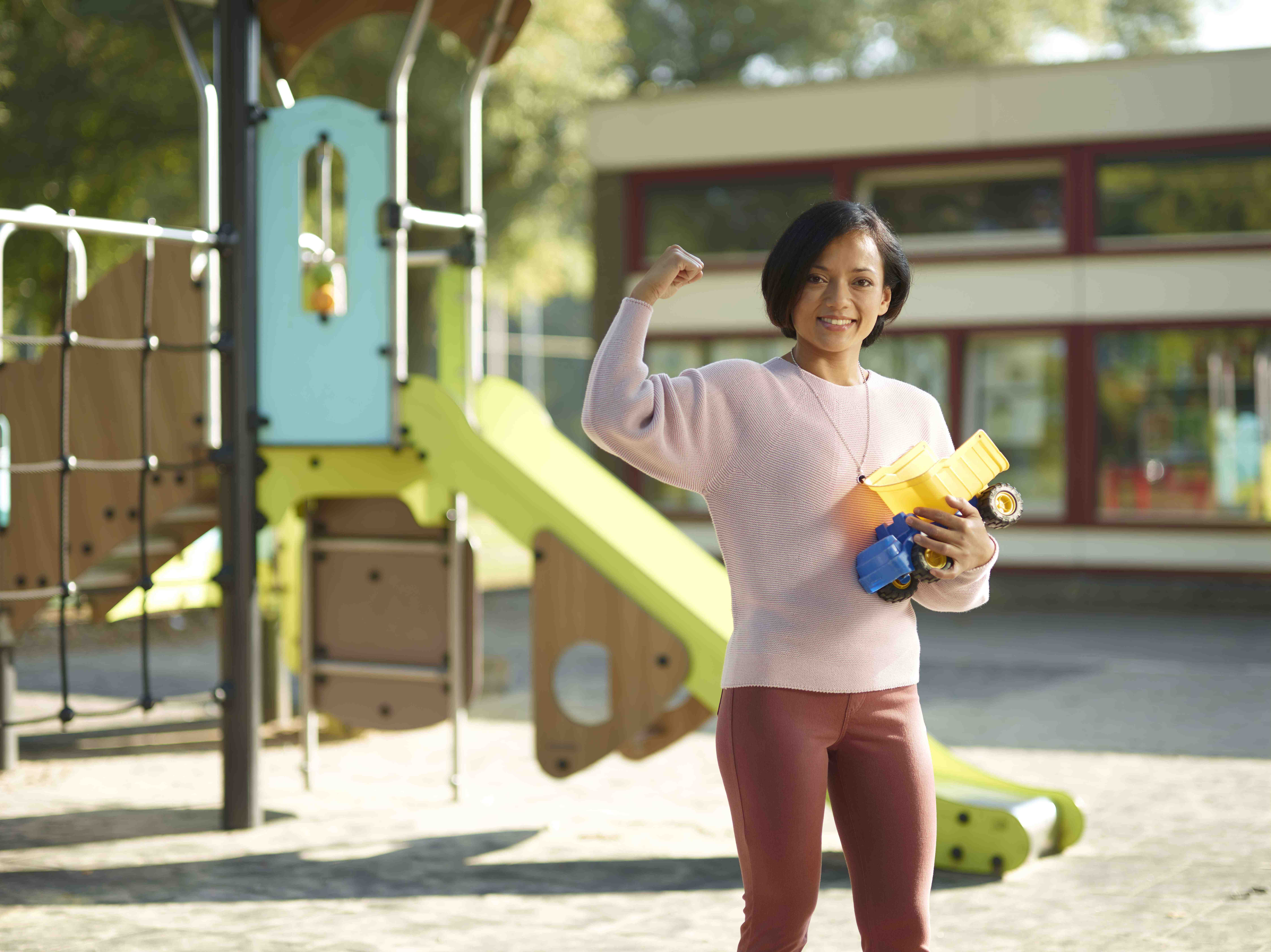 Pedagogisch Medewerker staat lachend in speeltuin