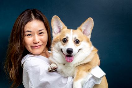 Dierenartsassistent lacht met hond in haar armen