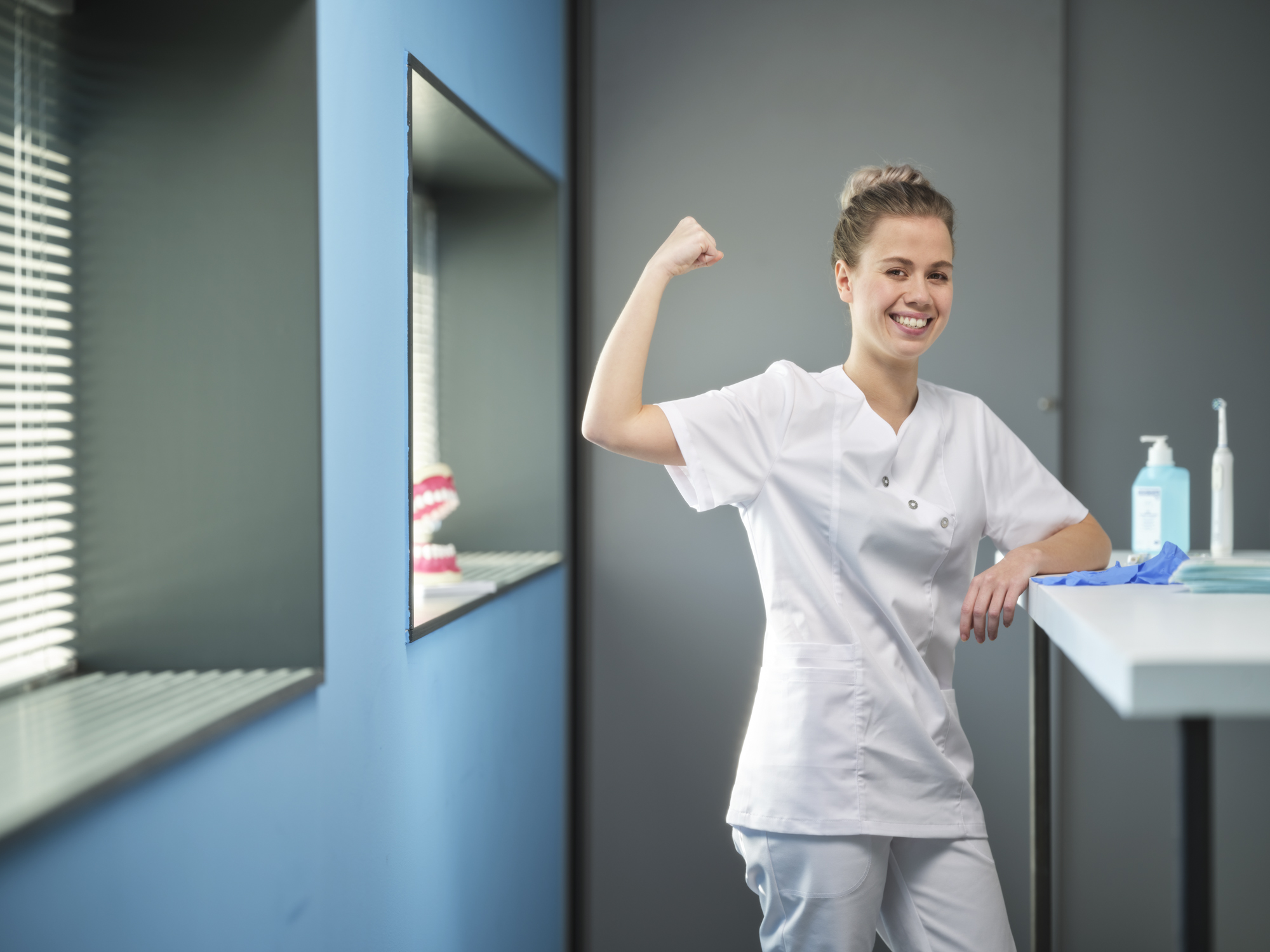 Tandartsassistent staat lachend achter balie met spierbal