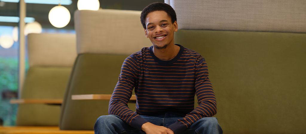 Een omscholende man zit op een bankje en lacht naar de camera