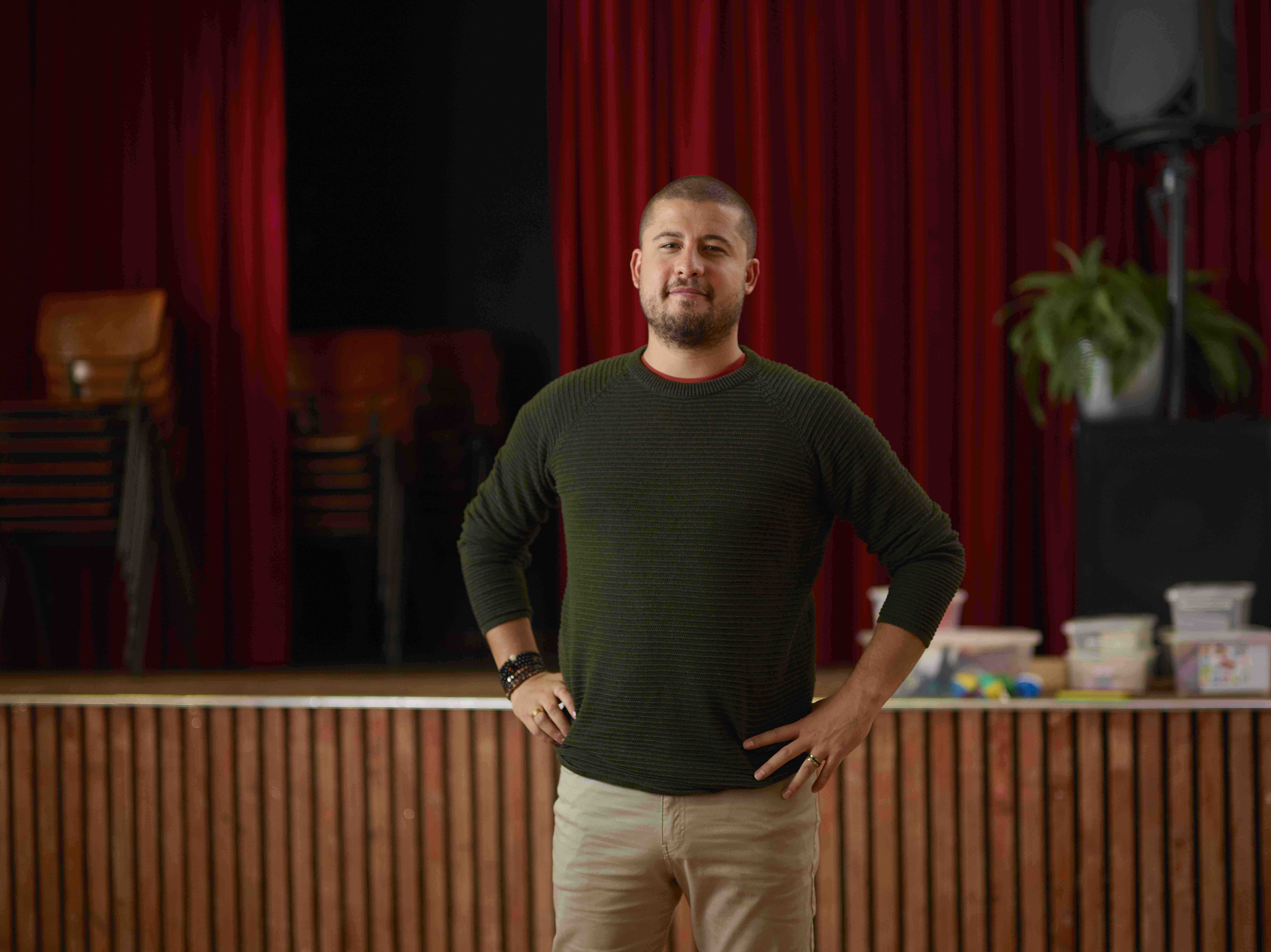 Sociaal werker staat lachend voor schoolpodium 